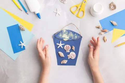 Paper bucket of shells summer idea for kids craft in kindergarten hands ocean's Stock Photos