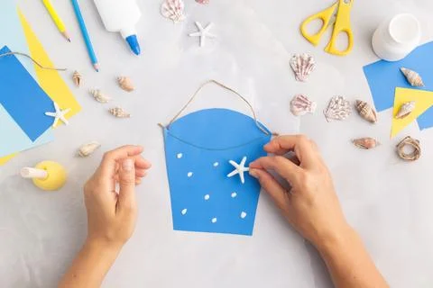 Paper bucket of shells summer idea for kids craft in kindergarten hands ocean's Stock Photos