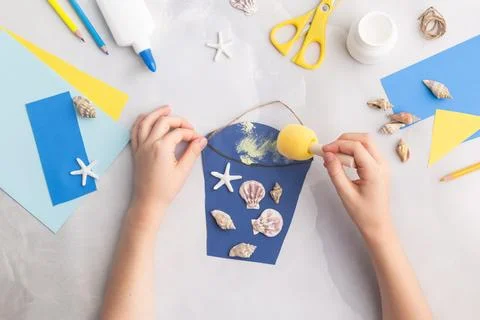 Paper bucket of shells summer idea for kids craft in kindergarten hands ocean's Stock Photos