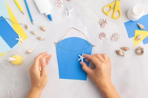 Paper bucket of shells summer idea for kids craft in kindergarten hands ocean's Foto stock
