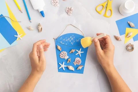 Paper bucket of shells summer idea for kids craft in kindergarten hands ocean's Stock Photos