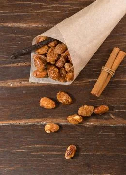 Paper bundle with roasted almonds on a rustic wooden background. Top view, close 库存照片