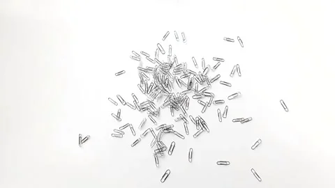 Paper clips slowly fall onto the table Stock Footage 135342284