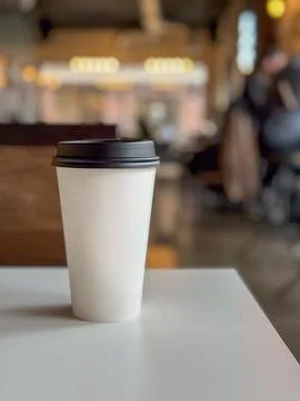 Paper coffee cup on a table in a coffee shop with a blurred background Stock Photos