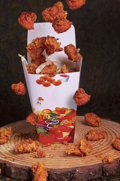 Paper container with fried crispy chicken popcorn nuggets on marble backgroun Stock Photos