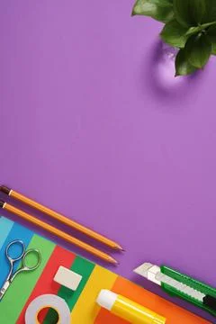 Paper craft table: scissors, knife, pencil, eraser, colored paper on purple b Stock Photos