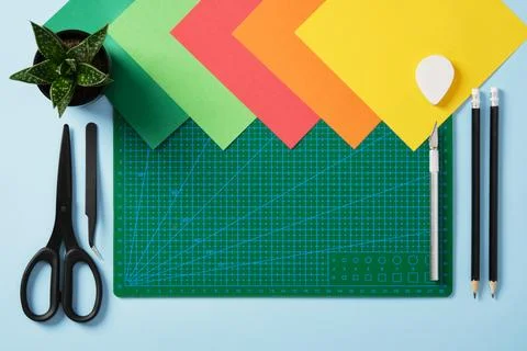 Paper crafts work table flatlay. Tools for hobby, green cutting mat, scissors Stock Photos