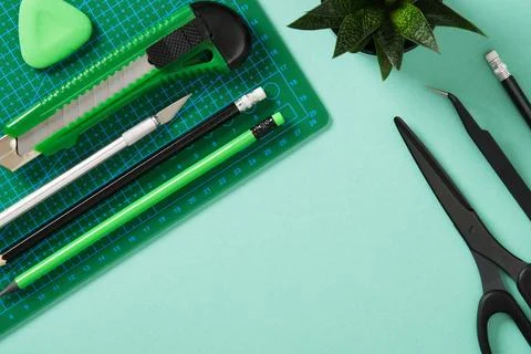 Paper crafts work table flatlay. Tools for hobby, green cutting mat, scisso.. Stock Photos
