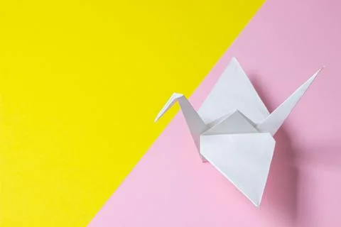 Paper crane on a geometric background. Colored background. Stock Photos