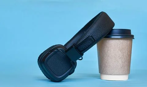 A paper cup for coffee and wireless headphones. Stock Photos