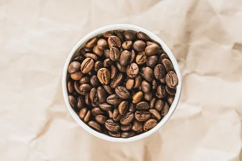 Paper cup filled with grains of fried coffee. Stock Photos