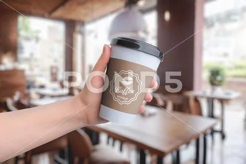 Paper cup mockup, held in hand at a coffee shop Plantilla PSD