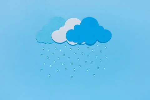Paper cut clouds with rain drops on blue background. Stock Photos