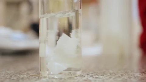 Paper cut was thrown into a flask of water and dissolved by stirring . Stock Footage 308717326