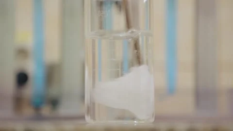 Paper cut was thrown into a flask of water and dissolved by stirring Stock Footage 308718573