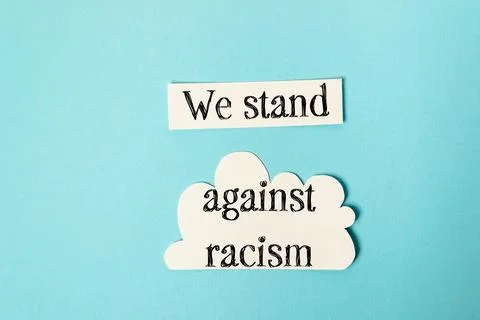 Paper cutouts with message promoting unity and standing against racism on blue Stock Photos
