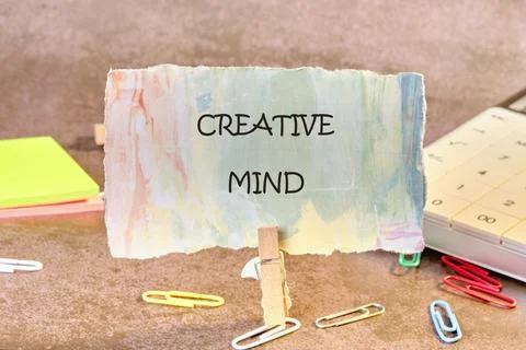 A paper displaying CREATIVE MIND is held by a clothespin among colorful Stock Photos