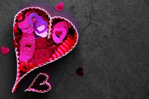 Paper elements in shape of heart on dark stone background. Love and Valentine Foto stock