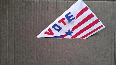 Paper envelope marked vote sliding into a grey cardboard ballot box Stock Photos