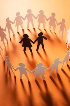 Paper figure of a couple surrounded by circle of paper people holding hands on Stock Photos