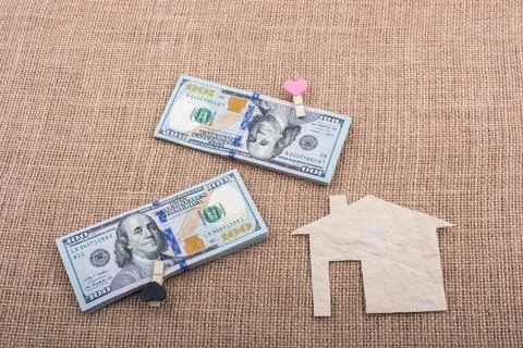 Paper house placed beside a bundle of US dollar banknote Stock Illustration