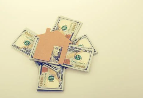Paper house placed beside a bundle of US dollar banknote 写真素材