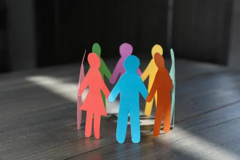 Paper human figures making circle on wooden table. Diversity and inclusion co Stock Photos