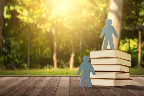 Paper human figures standing next to and on top of a stack of books, repres.. Stock Photos