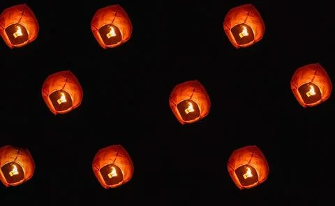 Paper lanterns in the night sky. Inside the lantern, the fire burns red. Stock Photos