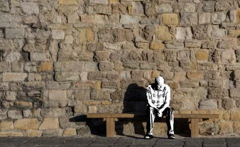 A paper Man sitting on a bench in front of an old stone wall Stock Illustration