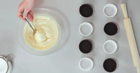 Paper muffin cases being filled with dough by chef Stock Footage 129328332