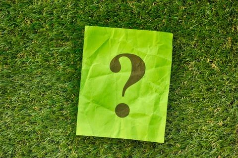 Paper note with question mark on green grass Stock Photos