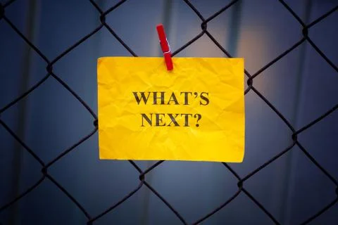 Paper note with question What is next hanging on a metal mesh fence Stock Photos