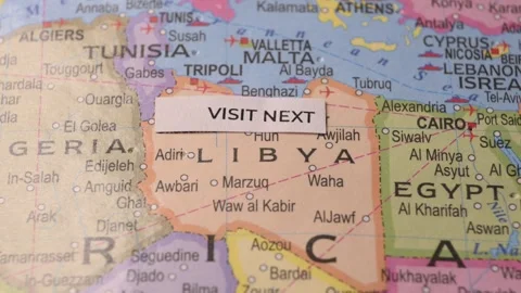 Paper note with Visit Next phrase placed on map pointing to Libya Stock Footage 346573194