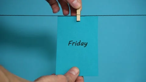 A paper note with the word friday hanging on a clothespin Stock Footage 294087494