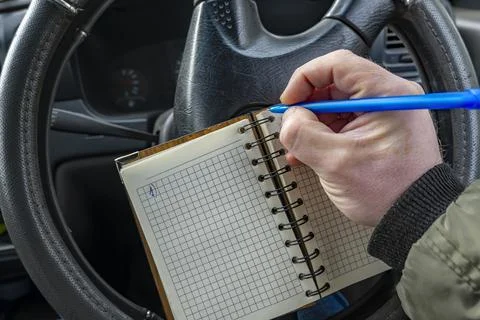 A paper notebook in the driver hand, in which a man writes notes Stock-Fotos