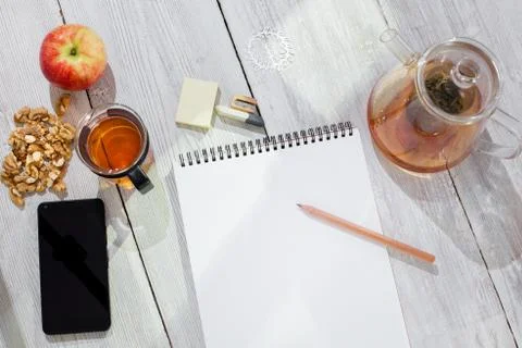 Paper notebook, pencil, cup of tea, apple, cellphone and walnuts on wooden table Stock Photos