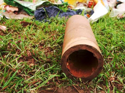 Paper object lying on green grass soil field with garbage stock on background 스톡 사진