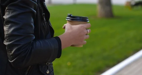 Paper or plastic cup of coffee in the hand of a girl  walking 库存影片 116539810