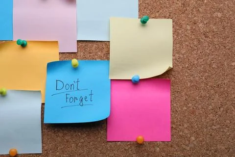 Paper with phrase Don't Forget and empty colorful notes pinned to cork boar.. Stock Photos