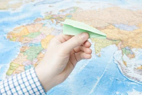 Paper plane in hand with world map on background Фото