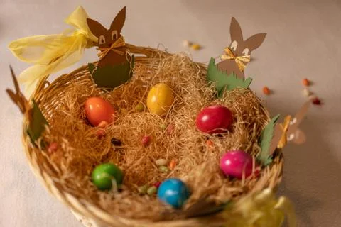 Paper rabbit sitting in basket with easter eggs. Stock Photos