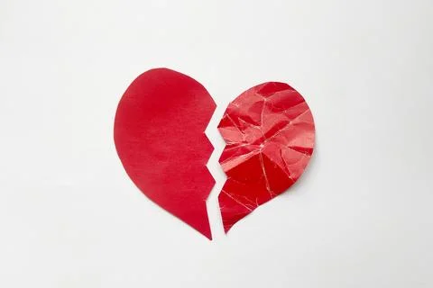 Paper red heart torn in half, one half crumpled symbolizing unrequited love Foto stock