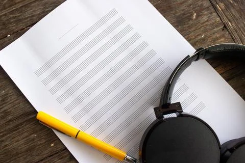 Paper sheet for musical notes with pen and headphone on wooden table. Stock Photos