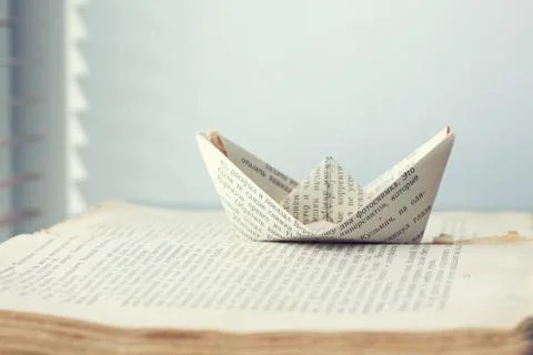 A paper ship is sent to the path of knowledge and words on sea book backgroun Stock Photos
