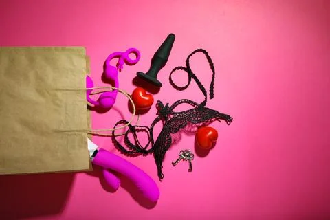 Paper shopping bag with different sex toys on red background, flat