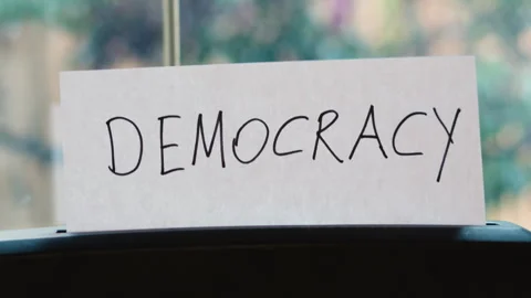 Paper Shredder Destroying Document with "DEMOCRACY" Text | Symbolic Concept of Stock Footage 331203425