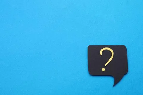 Paper speech bubble with question mark on light blue background, top view. .. Stock Photos