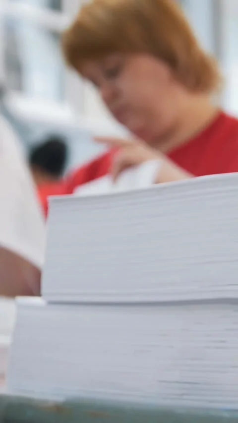 Paper stack in front of female worker sorting a papers in the typography Stock Footage 346706526