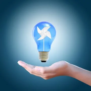 Paper windmill in a blue light bulb on women hand Stock Photos
